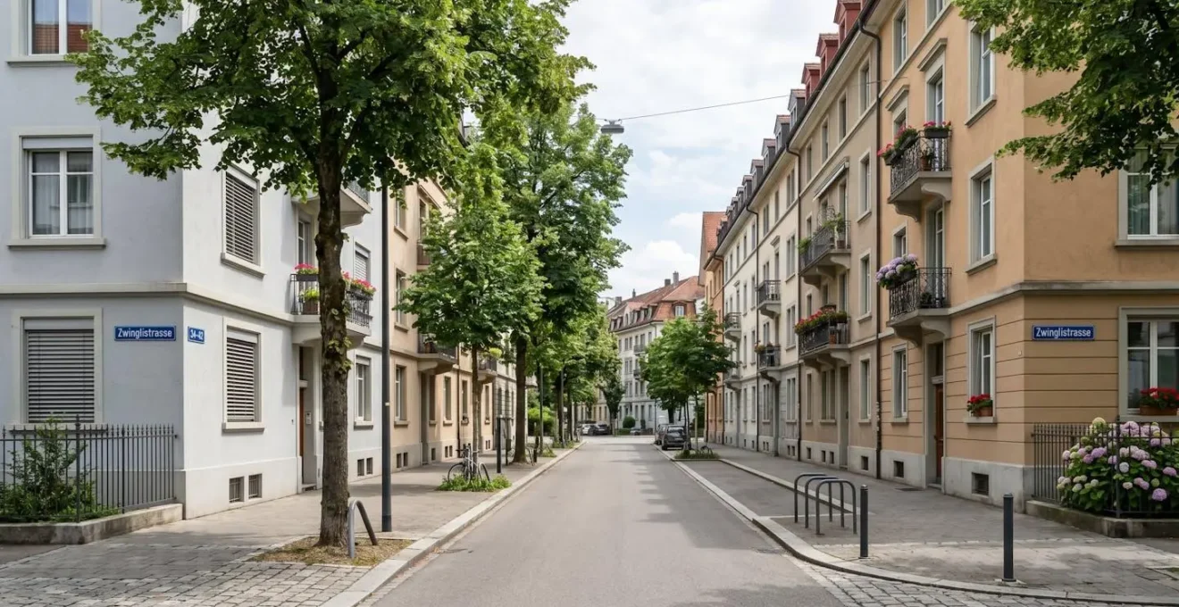 Weitwinkelaufnahme einer ruhigen Strasse im Basler Quartier Gundeldingen mit typischen Schweizer Mehrfamilienhäusern und Strassenbäumen bei Tageslicht