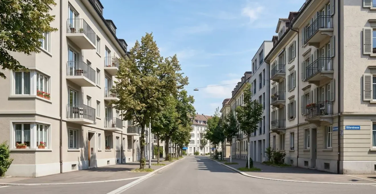 Weitwinkelaufnahme einer ruhigen Strasse im Basler Quartier Gundeldingen mit typischen Schweizer Mehrfamilienhäusern und Strassenbäumen bei Tageslicht
